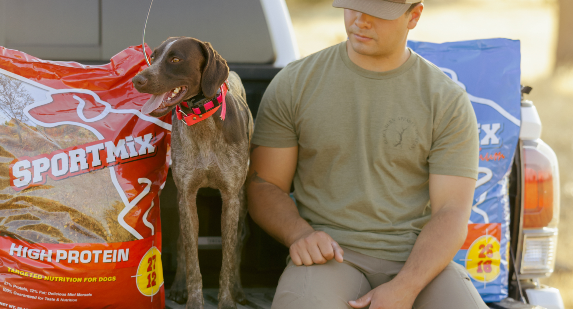 dog and owner sitting in the back of a truck.