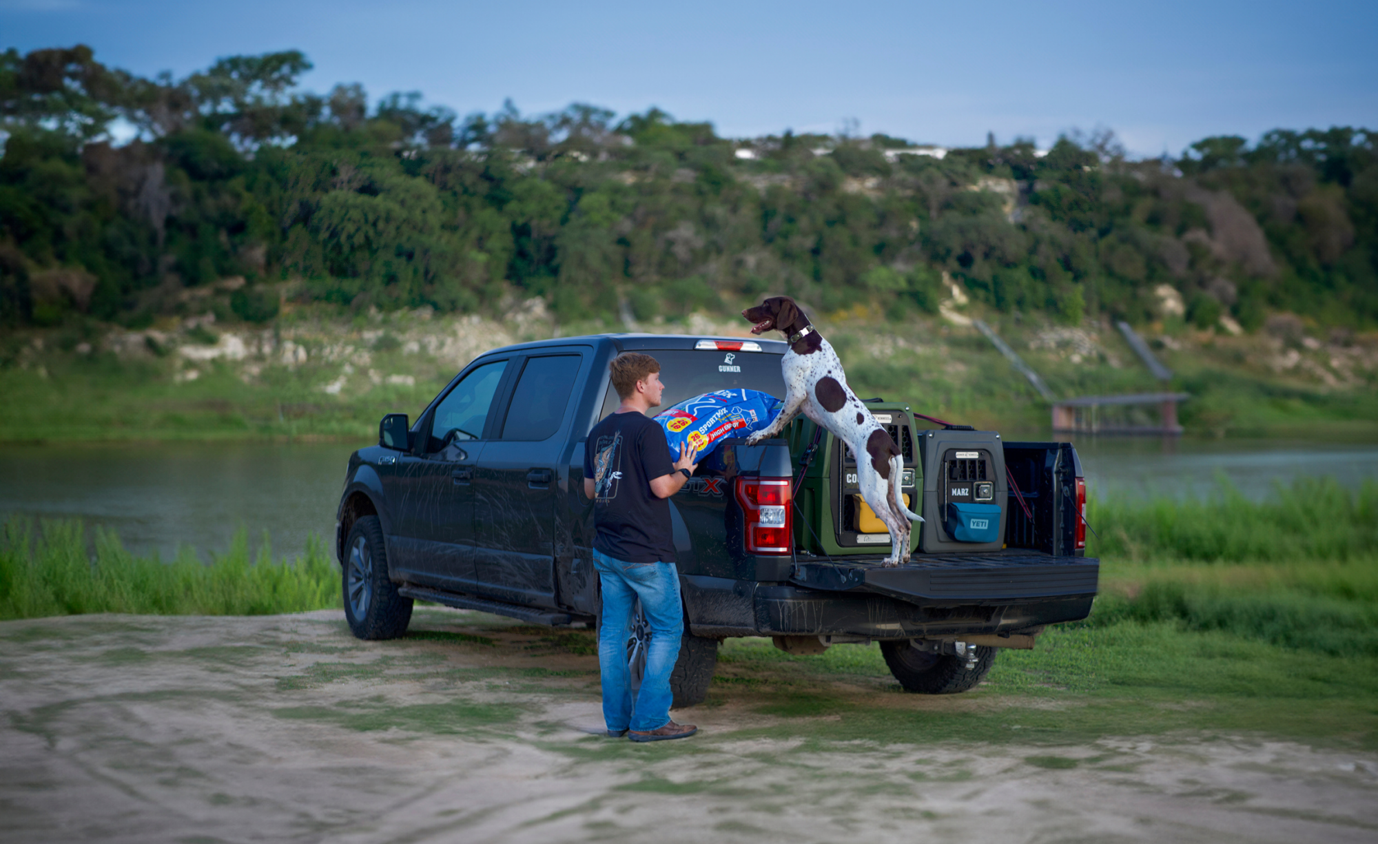 Man with dog in back of truck